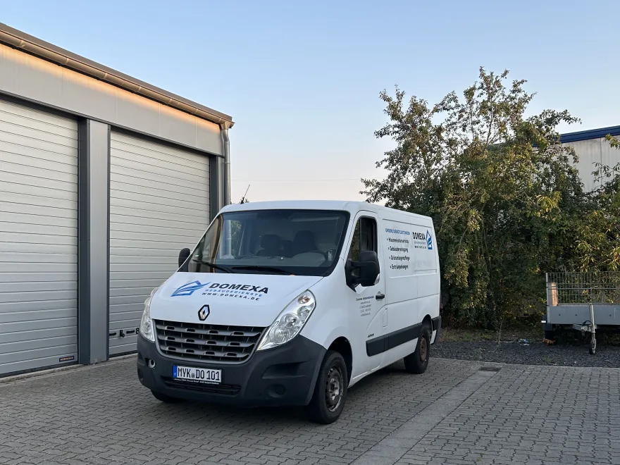 Firmenfahrzeug von Domexa mit Anhänger vor einer Garage