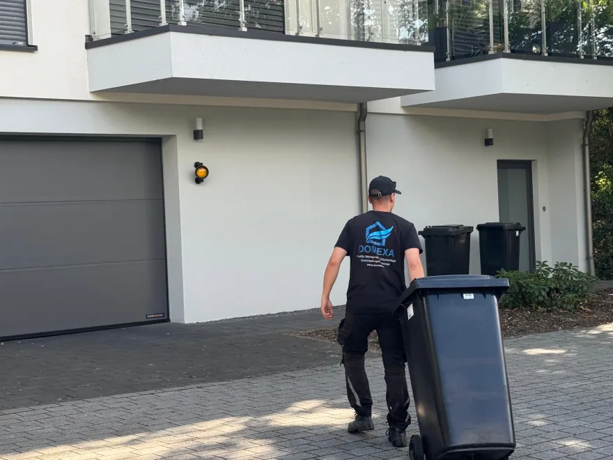Einer der Inhaber von Domexa stellt eine Mülltonne an einem Mehrfamilienhaus bereit